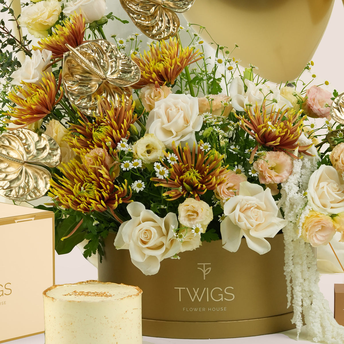Aurelia Celebration, a luxury TWIGS Gold Garden box arrangement of white and peach roses, chrysanthemums, and gold anthurium leaves, paired with a 1kg cake and three gold chrome balloons.