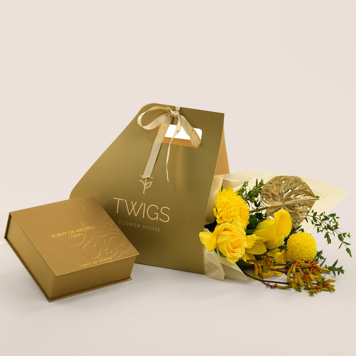 Solara, a TWIGS Gold carry bag with yellow roses, chrysanthemums, and a gold anthurium leaf accent, paired with the Contemplation Gift Set by Light of Sakina.