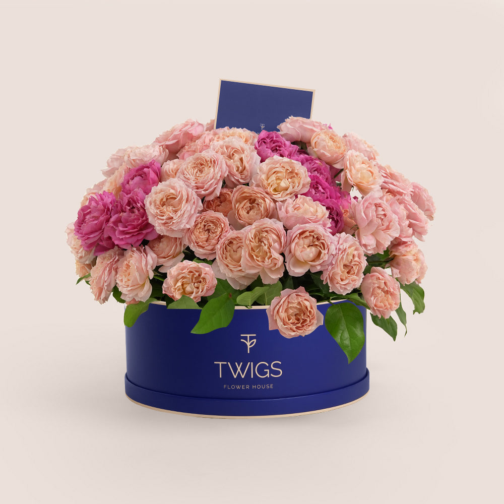 Grande round flower box with premium Juliet spray roses and cerise accents in TWIGS beige or green packaging, available for same day flower delivery in Abu Dhabi when you buy flowers online.