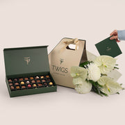 White anthurium and magnum chrysanthemum bouquet in TWIGS beige or green BUNCH sleeve packaging, bundled with a 32-piece chocolate box, available for same day flower delivery in Dubai when you buy flowers online.