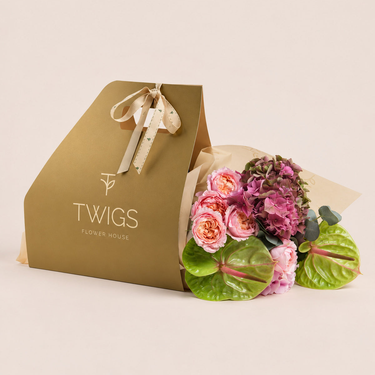 Isadora, a TWIGS Gold carry bag with garden roses, pink hydrangeas, and green anthurium leaves, on a light beige background.
