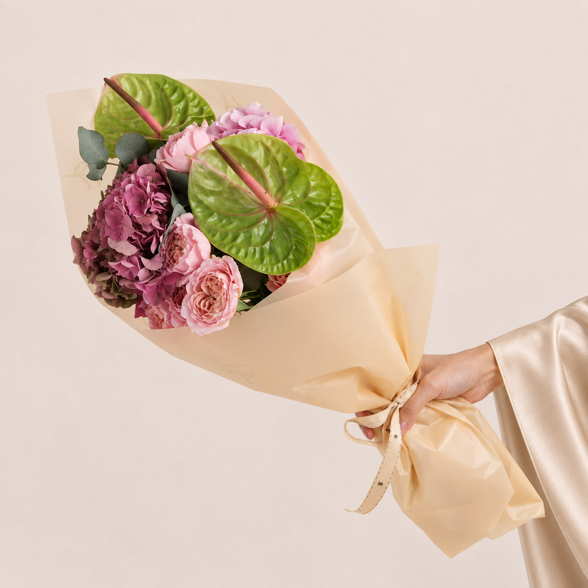 Isadora, a TWIGS Gold carry bag with garden roses, pink hydrangeas, and green anthurium leaves, on a light beige background.
