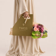 Isadora, a TWIGS Gold carry bag with garden roses, pink hydrangeas, and green anthurium leaves, on a light beige background.
